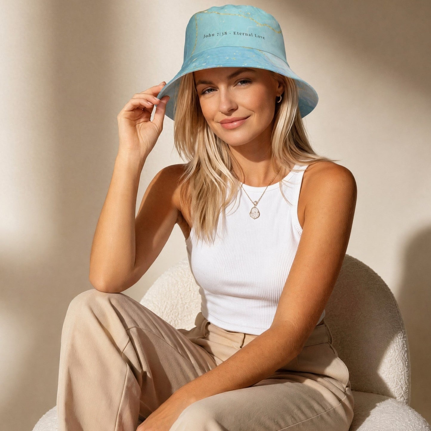 Model wearing the Living Waters reversible bucket hat, turquoise and gold design, John 7:38.